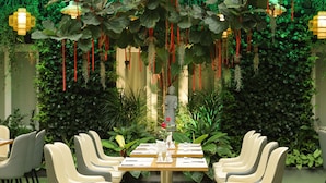 A restaurant with a green wall backdrop, hanging plants, and a Buddha statue. - Pleiku Hotel by Gia Lai Tourist (Pleiku)