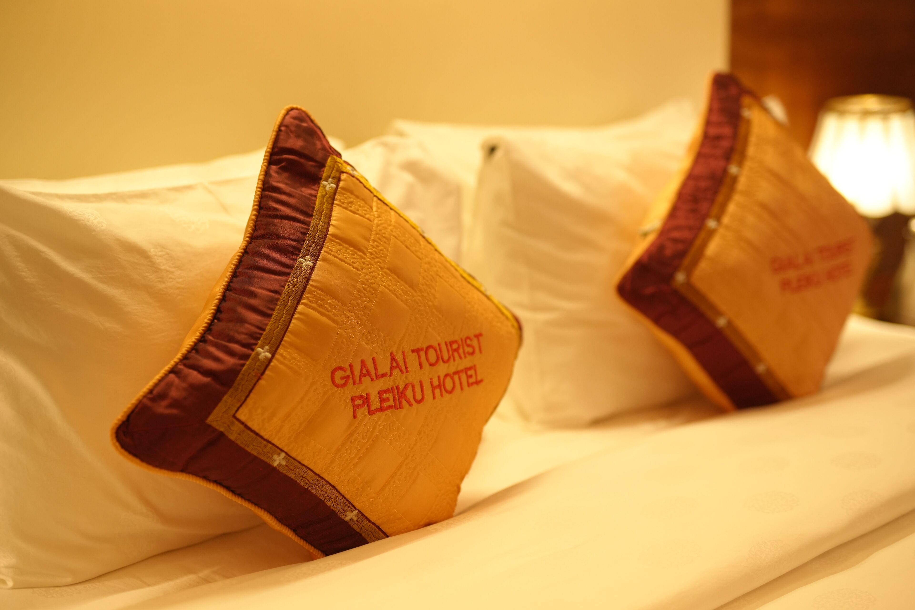 Una cama de hotel con almohadas que dicen "GIALAI TOURIST PLEIKU HOTEL".