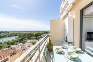 A balcony with a table set for dining, overlooking a river and greenery.