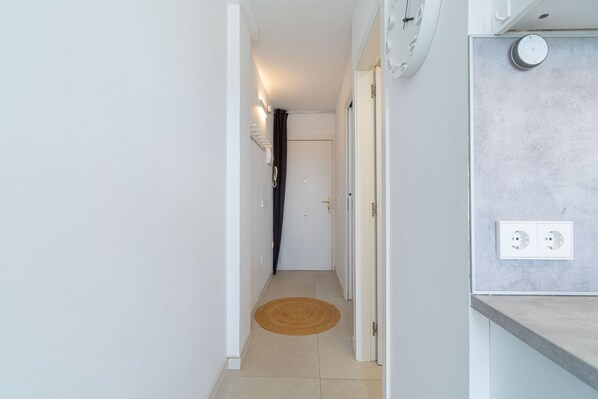 A narrow hallway with a brown mat, white walls, and a door at the end. - 0116-MUGA PARK Apartment with river and sea view (Empuriabrava)