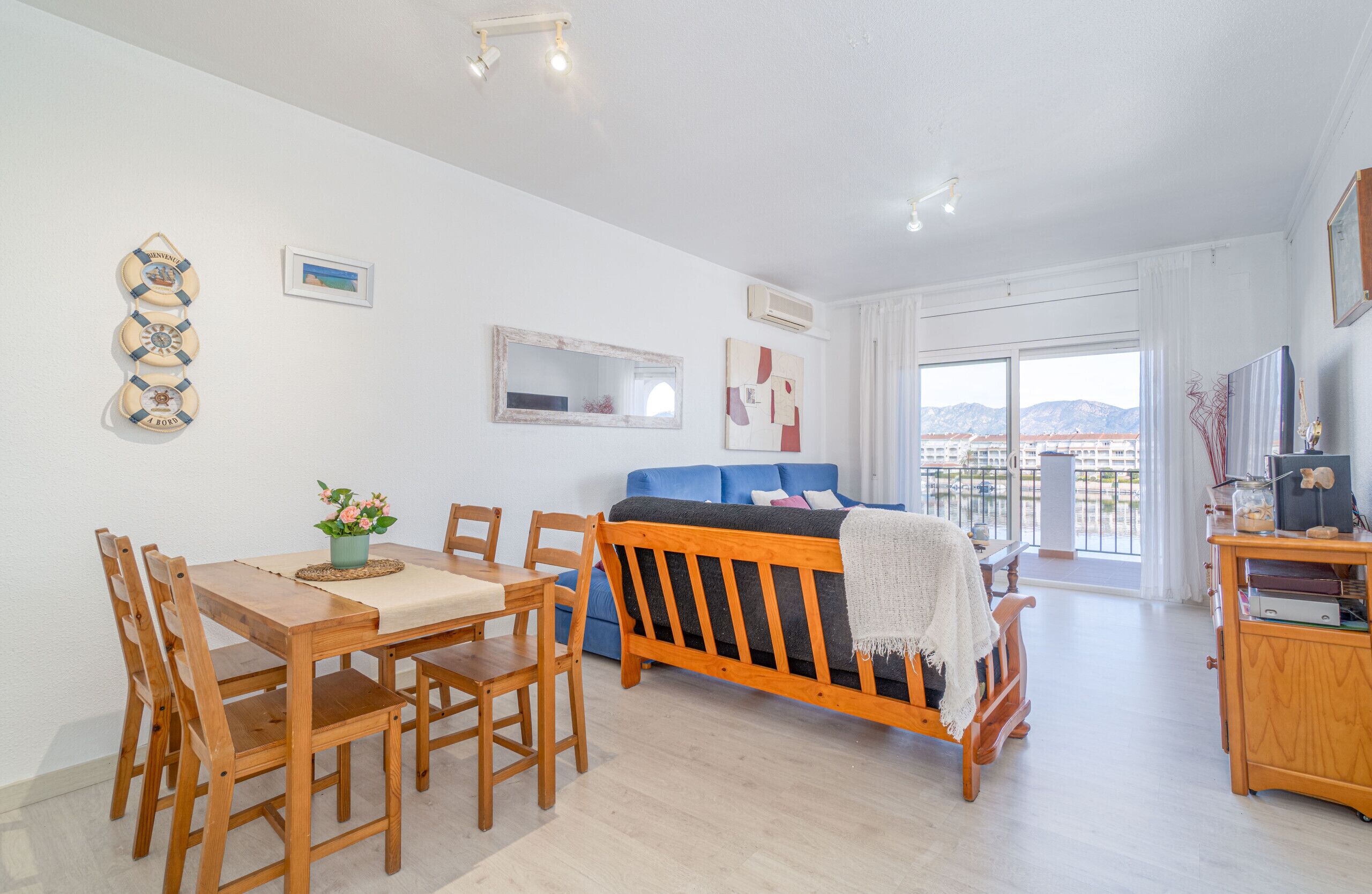 Een moderne woonkamer met een houten eettafel, stoelen, een bank en een tv-meubel.