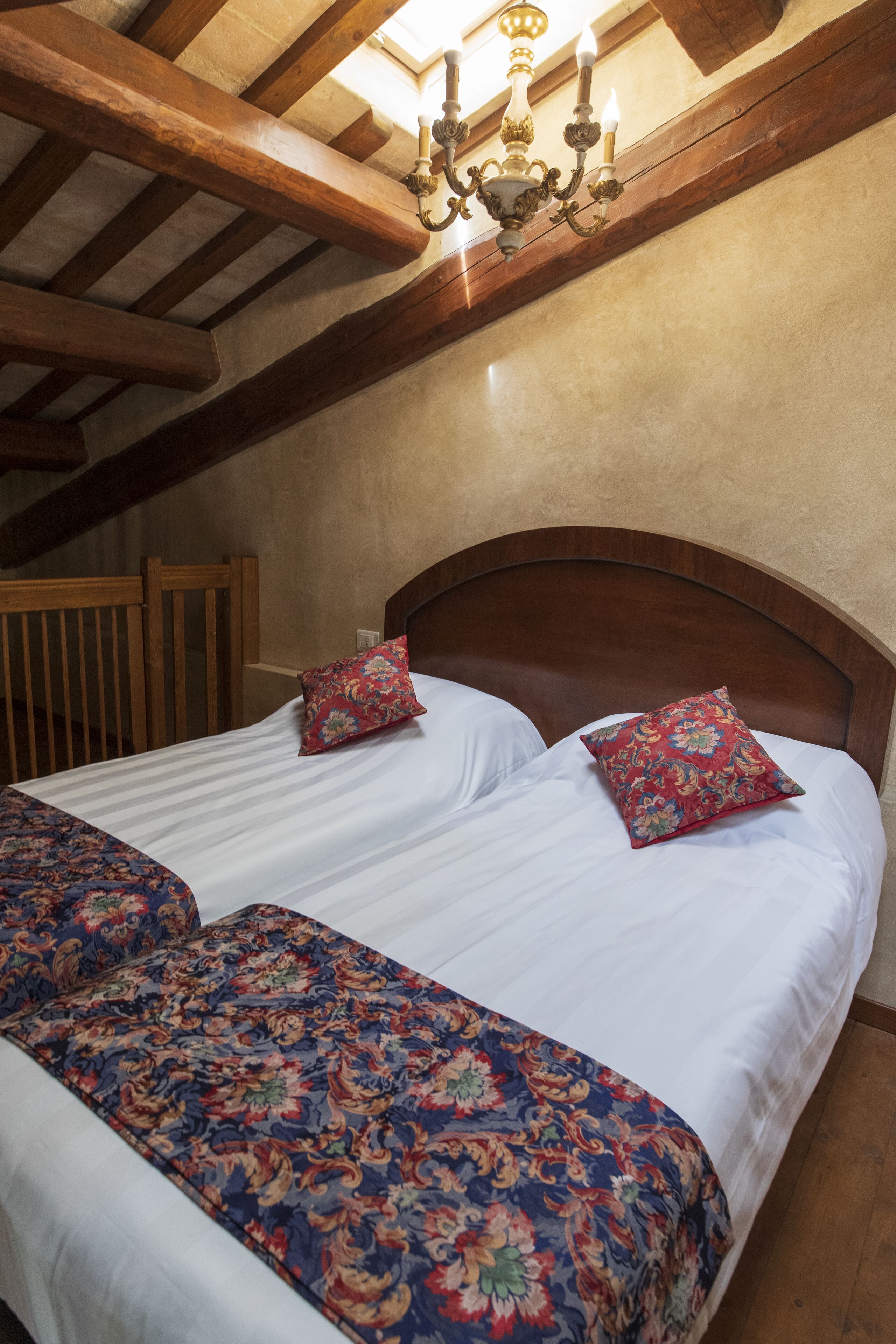 A bedroom with a wooden headboard, two floral-patterned pillows, and a bed with a striped bedspread.