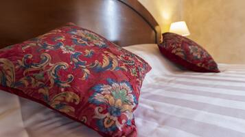 Una cama con cabecera de madera, ropa de cama a rayas y dos almohadas decorativas.