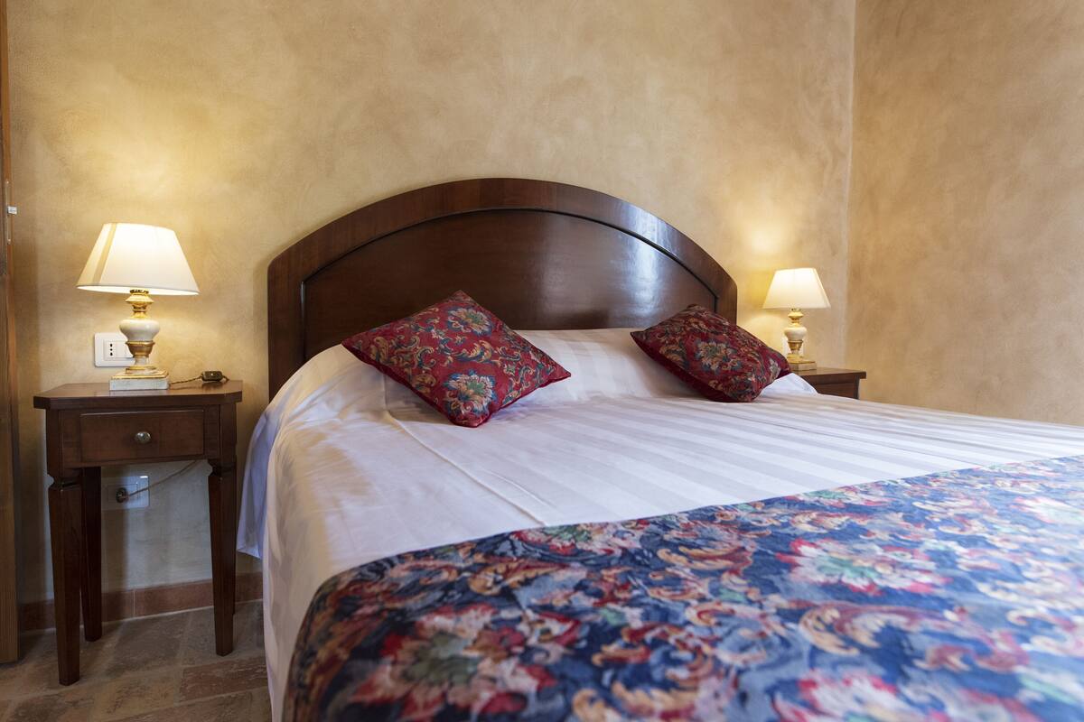 A hotel room with a large bed, two nightstands, and two lamps.
