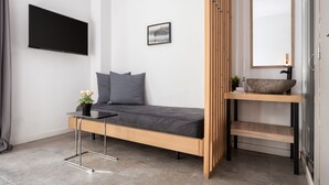 A modern bedroom with a bed, a bedside table, a mirror, and a wall-mounted TV. - Acropolis Cozy Living (Athens)