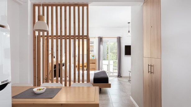A modern kitchen with a wooden table, a bowl of fruit, and a white refrigerator. - Acropolis Cozy Living (Athens)