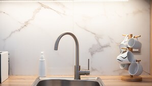 A modern kitchen with a stainless steel sink, a marble backsplash, and a wooden countertop. - Acropolis Cozy Living (Athens)