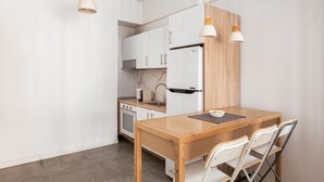 A modern kitchen with white cabinets, a wooden table, and two pendant lights. - Acropolis Cozy Living (Athens)