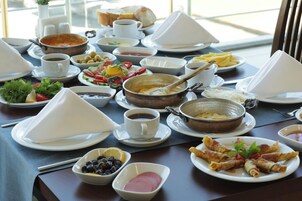 Un bufé de desayuno con diversas opciones de comida, entre ellas frutas, verduras y pan.