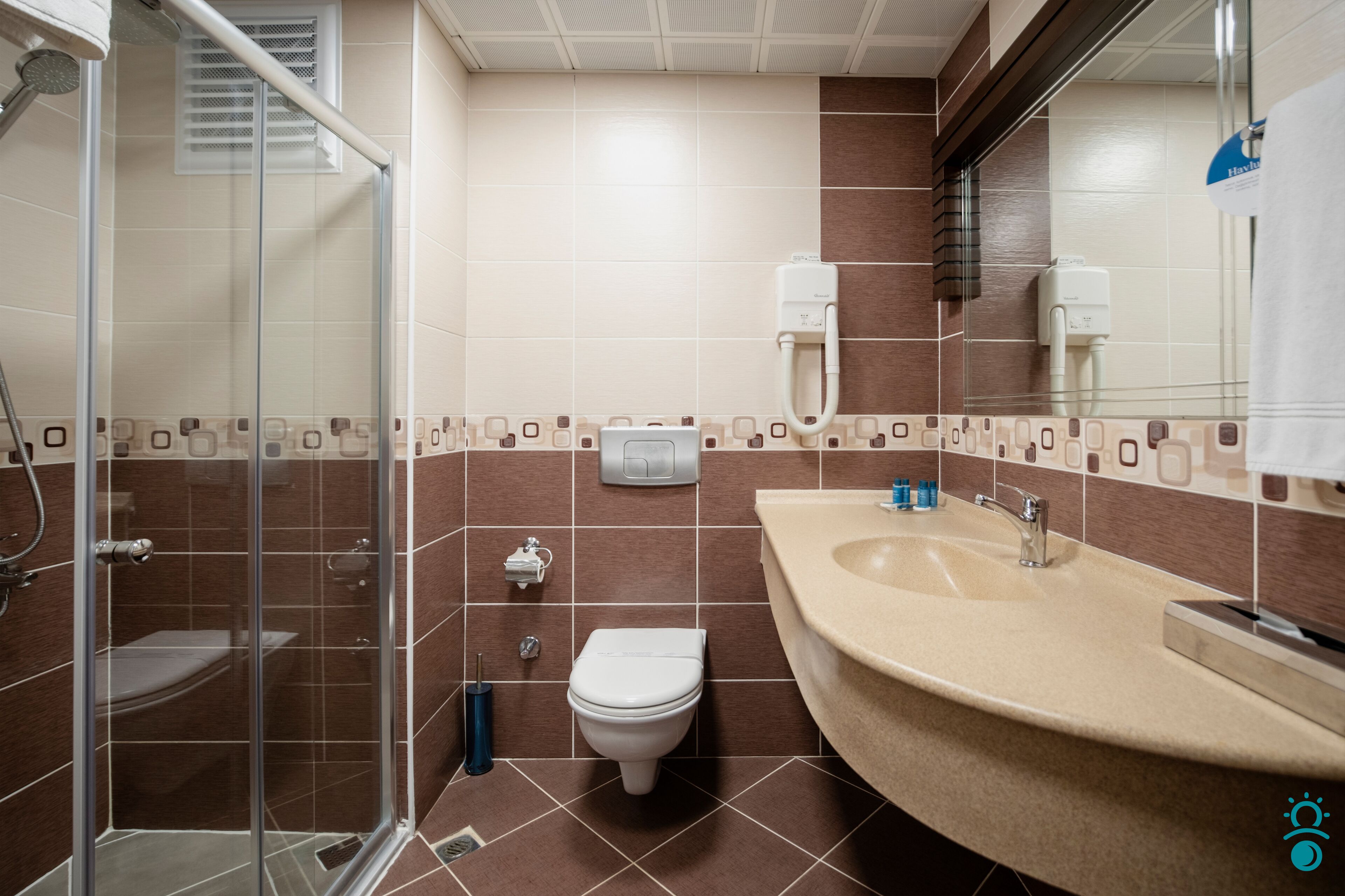 A modern bathroom with a glass-enclosed shower, a beige sink, and a toilet.