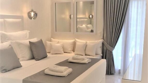 Ein modernes Hotelzimmer mit einem großen Bett, Nachttischen, einem Spiegel und Blick ins Freie.