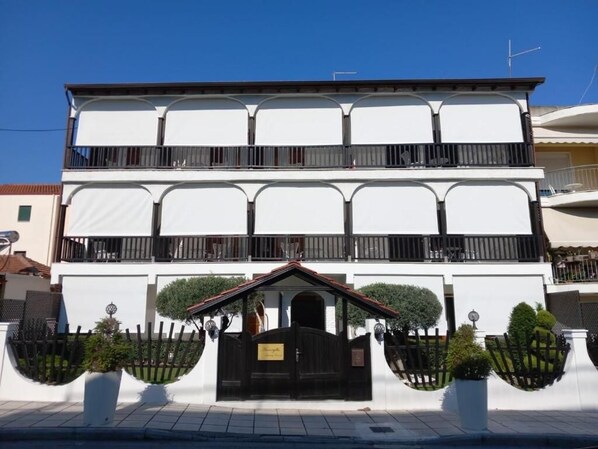 A two-story building with a symmetrical facade, a central entrance with a black gate, and two balconies on the upper floor.