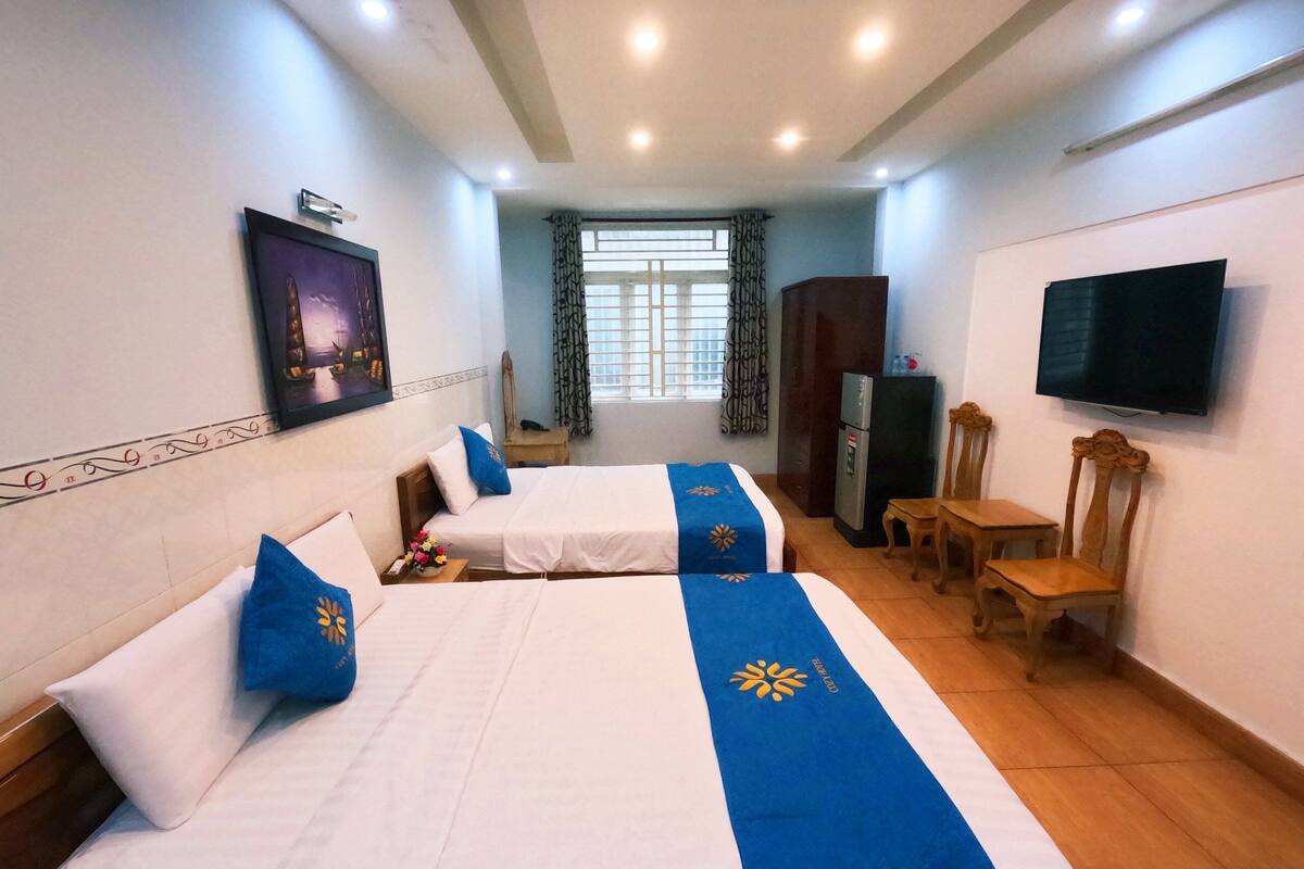 Habitación de hotel con dos camas, televisor, escritorio y una silla.