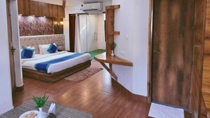 A modern bedroom with a bed, wooden floor, and a door. - Royals Moonlight Resort (Kaladhungi)