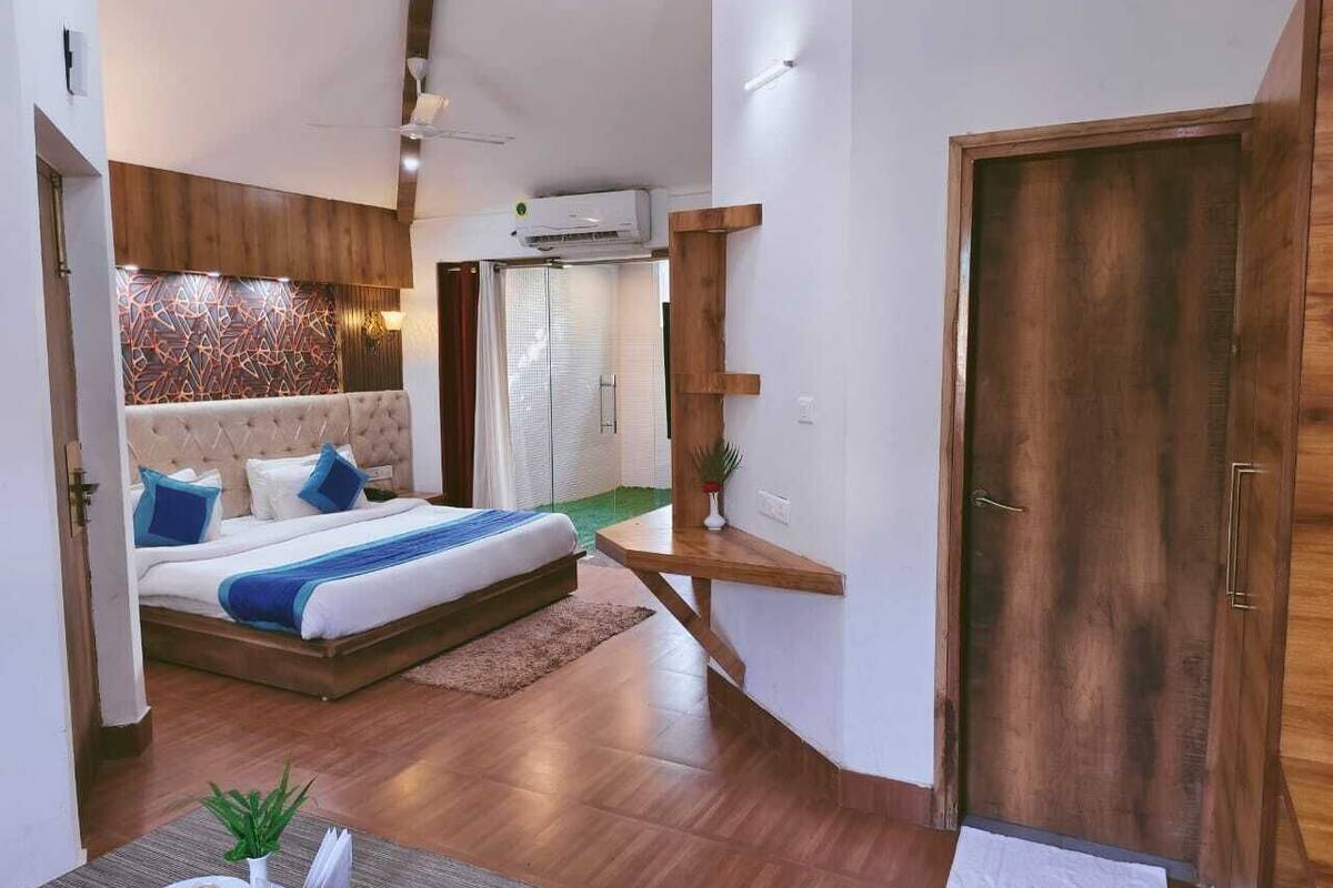 A modern bedroom with a bed, wooden floor, and a door.