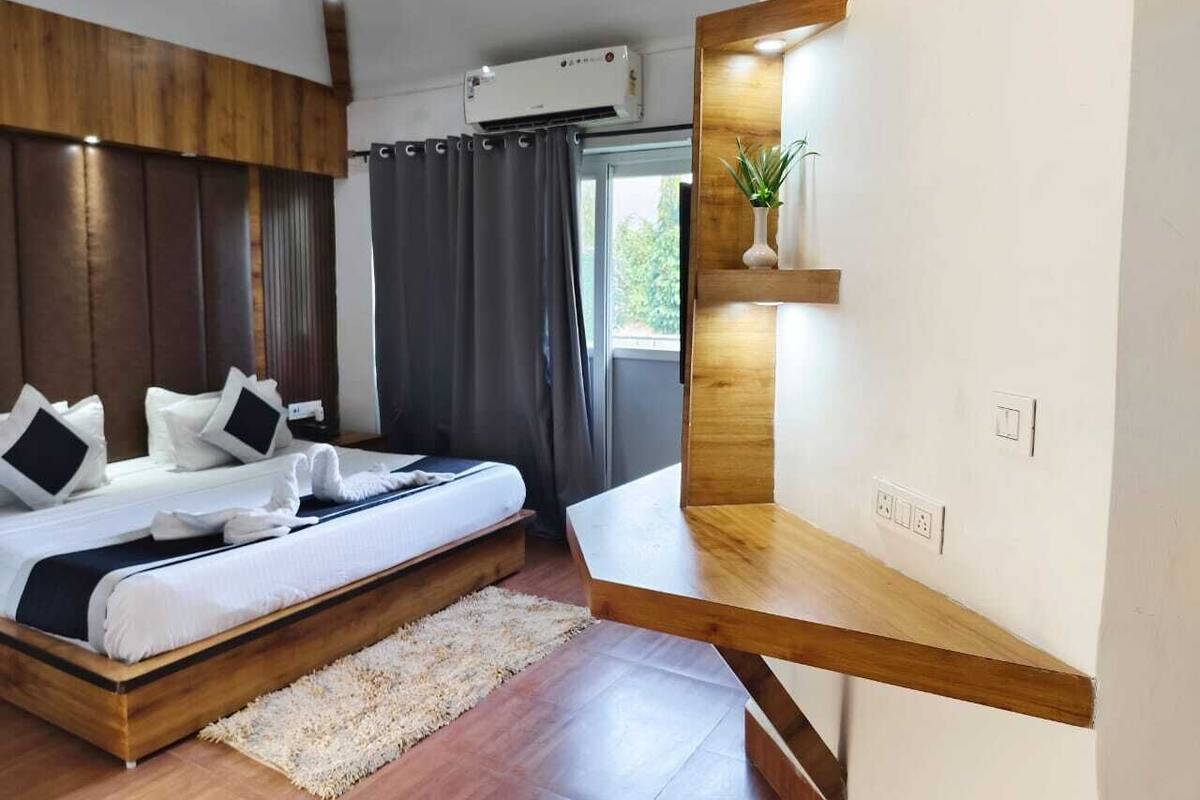 A modern bedroom with a wooden bed, a built-in shelf, and a large window with curtains.