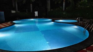 A swimming pool with a tiled deck and a signboard in the background. - Royals Moonlight Resort (Kaladhungi)