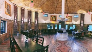 A spacious restaurant with a central island, high ceilings, and artwork on the walls. - Royals Moonlight Resort (Kaladhungi)