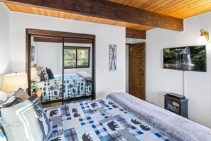 Een slaapkamer met een bed, nachtkastje, lamp, televisie en een raam.
