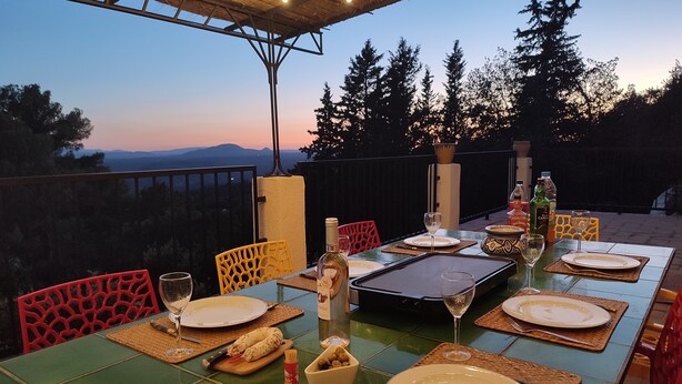 An outdoor dining area with a table set for four, surrounded by chairs, and overlooking a scenic view of trees and mountains. - Villa in Provence's sky - 300m from center - Private pool and panoramic view (Tourtour)