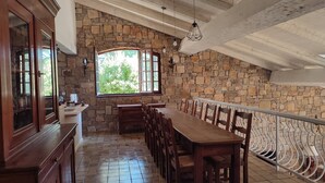 A dining area with a stone wall, wooden furniture, and a view through a window. - Villa in Provence's sky - 300m from center - Private pool and panoramic view (Tourtour)