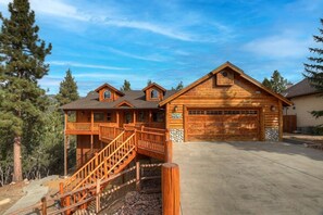 A two-story log cabin with a covered porch and a garage.