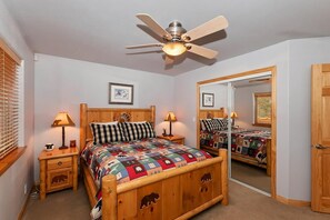 A bedroom with a wooden bed, two bedside tables, a ceiling fan, and a mirror.