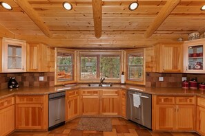 A kitchen with wooden cabinets, a dishwasher, and a window with a view of the outdoors.
