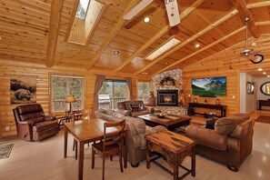 A log cabin interior with a fireplace, wooden furniture, and a television. - Bear Pause By Destination Big Bear: Walking Distance to the Lake! Castle Glen Estates Log Cabin Home! PET FRIENDLY! Fully Fenced! Pool Table! HOT TUB! Boarders Eagle Preserve! (Big Bear Lake)