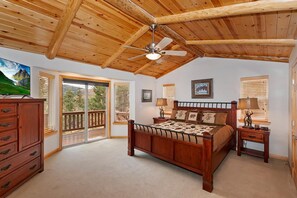 A bedroom with a wooden ceiling, a bed, a nightstand, a dresser, and a sliding glass door leading to a balcony.
