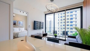 Une chambre d’hôtel moderne dotée d’une grande fenêtre, d’un téléviseur à écran plat, d’un bureau et d’un canapé.