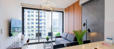 A modern living room with a sofa, a coffee table, a TV, and a balcony with a city view.