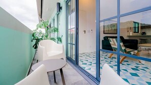 A balcony with white chairs and a small table, a glass door leading to a kitchen area, and a tiled floor with a geometric pattern. - w* | Spacious 1BR in Santa Ana (Panamá)