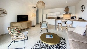 A modern living room with a sofa, two wicker chairs, a coffee table, and a TV. - Appartement T2 Neuf, les Terrasses de Ciaccone Proche mer et Montagne (Lecci)