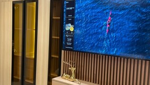 Ein an der Wand befestigter Fernseher zeigt einen Kajakfahrer auf dem Wasser.