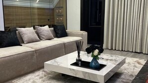 Ein modernes Wohnzimmer mit einem beigen Sofa, einem Marmor-Couchtisch und einer Vase mit Blumen.