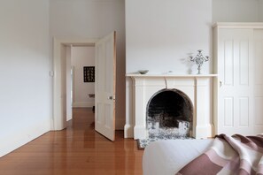Een kamer met een open haard, een bed met dekbed en een gang naar een andere kamer.