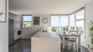 A modern kitchen with a central island, large windows, and a view of the sea. - Sea You Soon: Views, Parking & WiFi (Montello)
