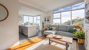 A modern living space with a kitchen, a grey sofa, and a dining area. - Sea You Soon: Views, Parking & WiFi (Montello)