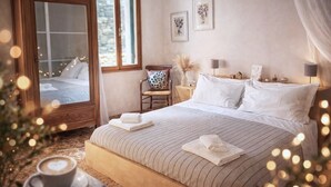 Un dormitorio con una cama grande, un armario de madera, una silla, una mesita de noche y dos lámparas fijadas a la pared.
