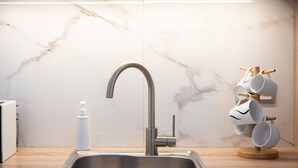 A modern kitchen with a stainless steel sink, a marble backsplash, and a wooden countertop. - Acropolis Cozy Living (Athina)