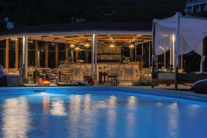 Zona junto a la piscina con bar y asientos.