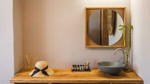 A bathroom with a wooden vanity, a round mirror, a bowl sink, and a bamboo plant. - Skiathos Avaton Garden (Skiathos)