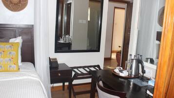 Une chambre d’hôtel équipée d’un lit, d’un bureau, d’une chaise, d’un grand miroir et d’une machine à café.