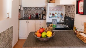 A kitchen with white cabinets, a fruit bowl on the counter, and a tiled backsplash. - Casa Peppenella in Positano (Positano)