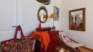 A room with a red dresser, a mirror, a lamp, and a colorful bag. - Casa Peppenella in Positano (Positano)