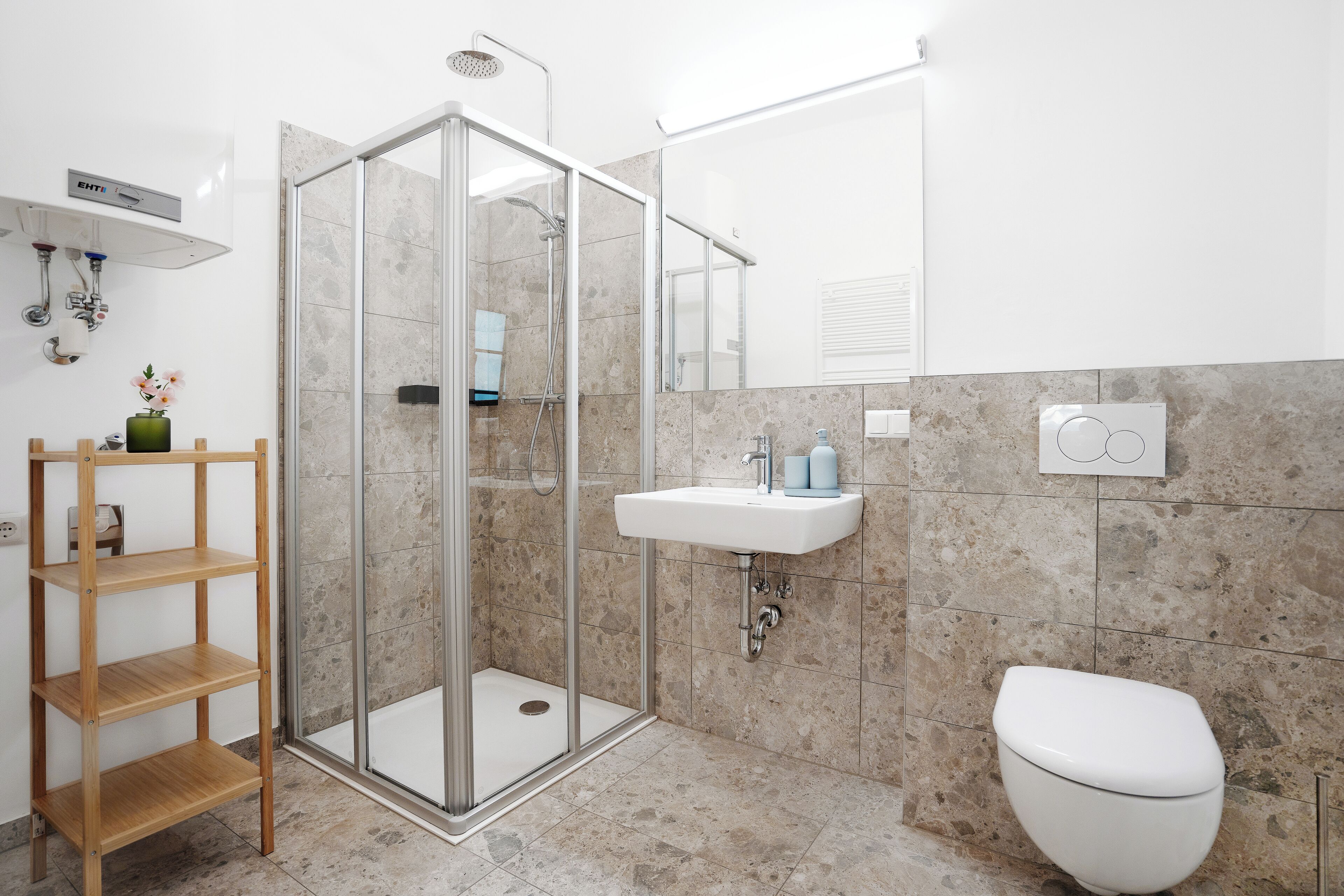 Een moderne badkamer met een douchecabine van glas, een witte wastafel en een toilet.