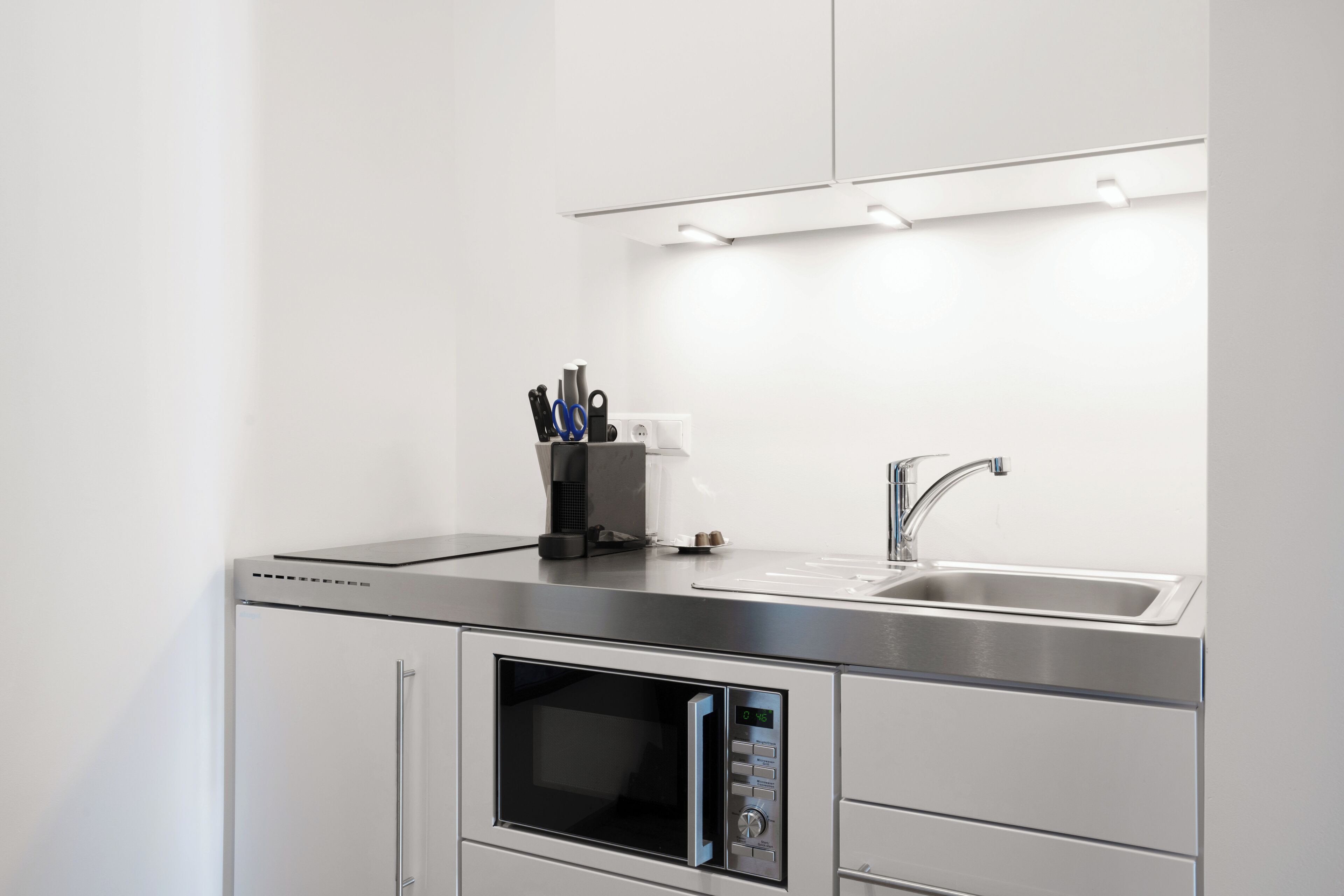 A modern kitchen with a stainless steel countertop, a built-in microwave, and a sink.