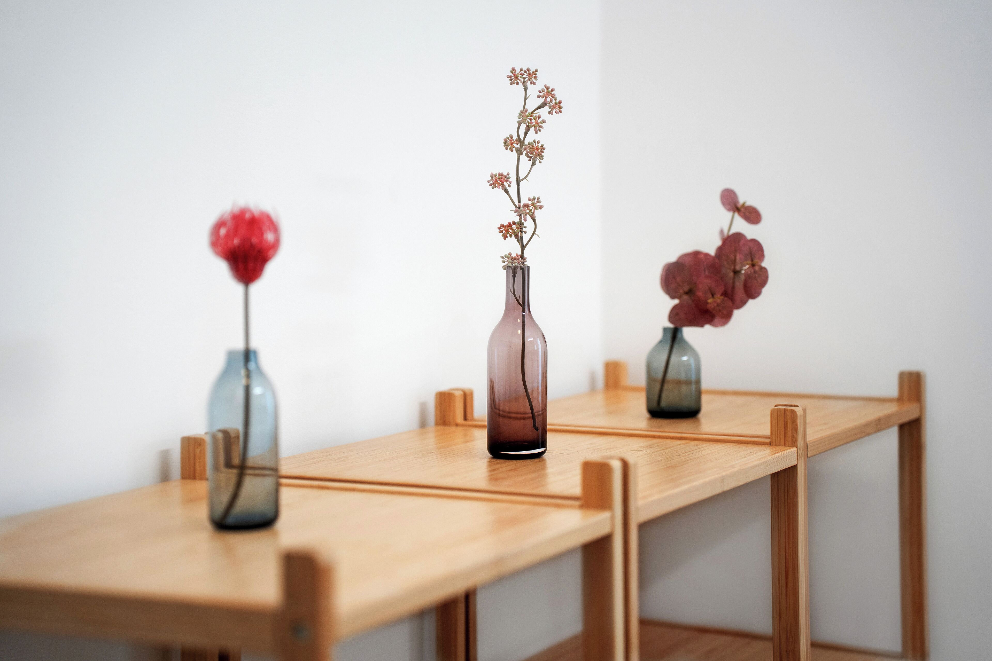 Una mesa de madera con tres jarrones que contienen flores.