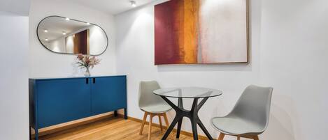 A modern meeting room with a blue cabinet, a round glass table, and two grey chairs.